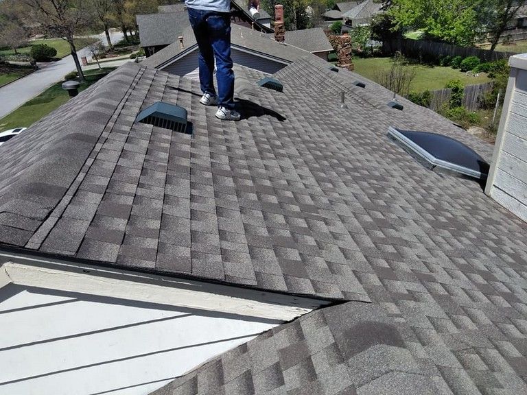 A man is standing on the roof of a house.