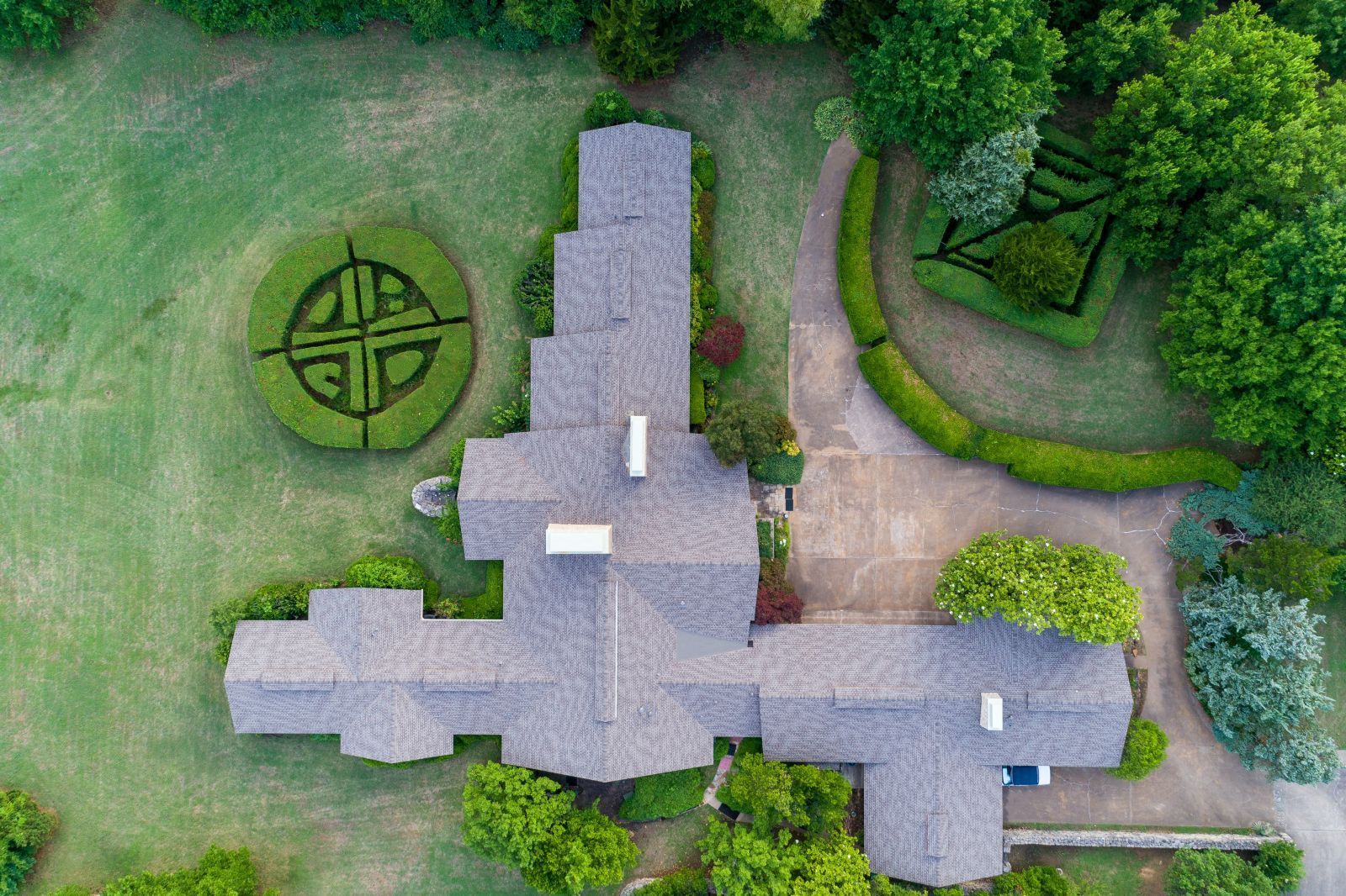 An aerial view of a large house surrounded by trees and bushes.