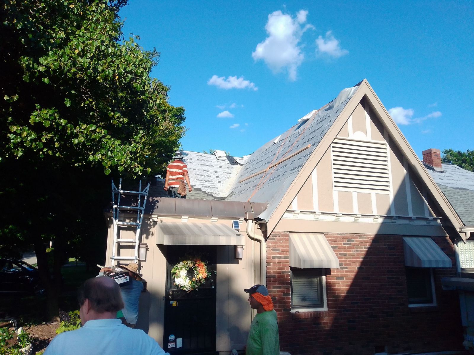A man standing in front of a house with a ladder on the roof