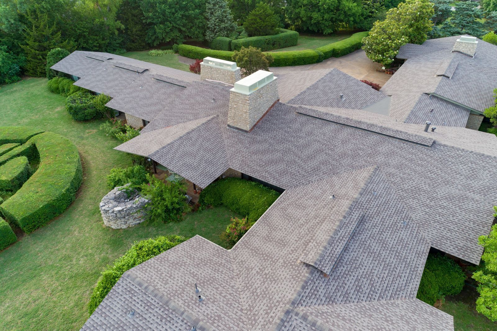 An aerial view of a large house surrounded by trees and bushes.