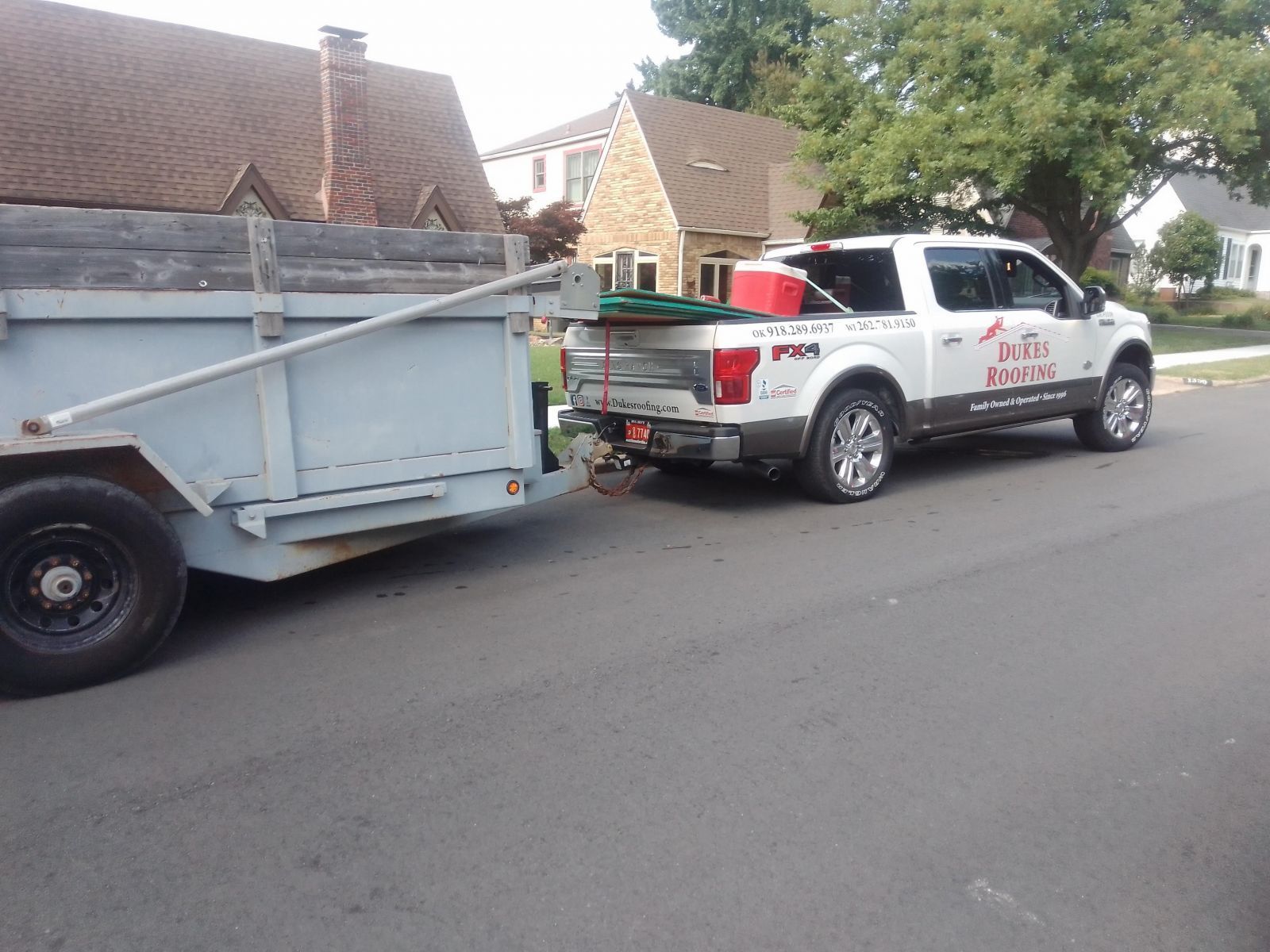 A truck with a trailer attached to it is parked on the side of the road