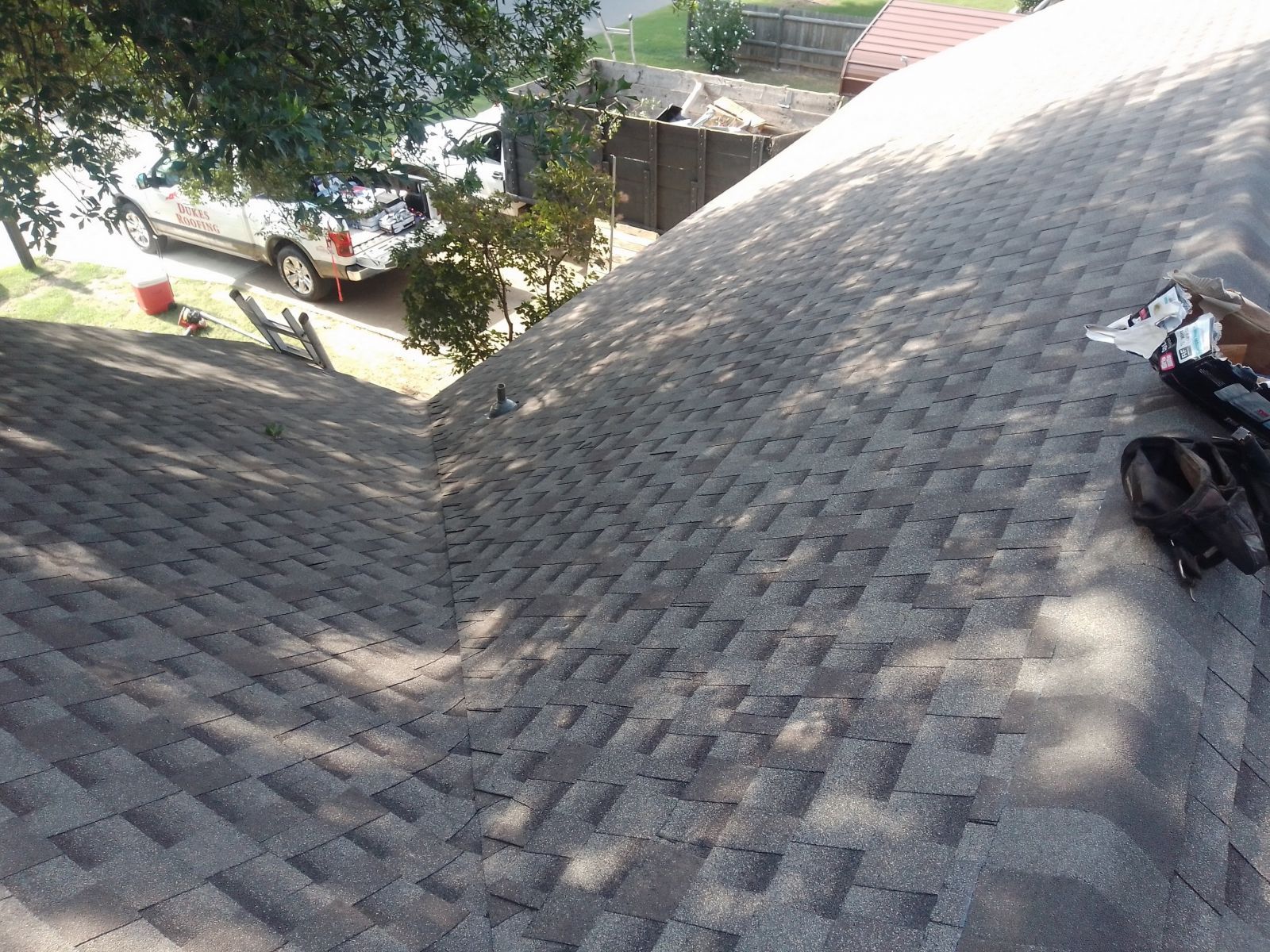A person is standing on top of a roof looking down at it.