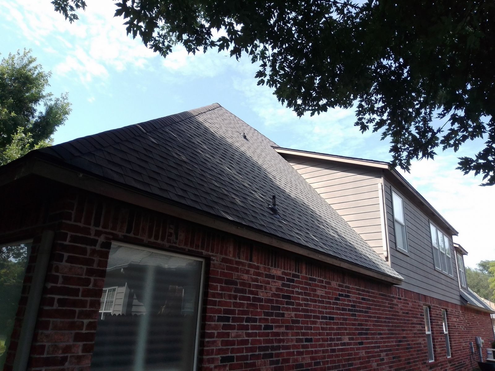 A brick house with a roof that has shingles on it