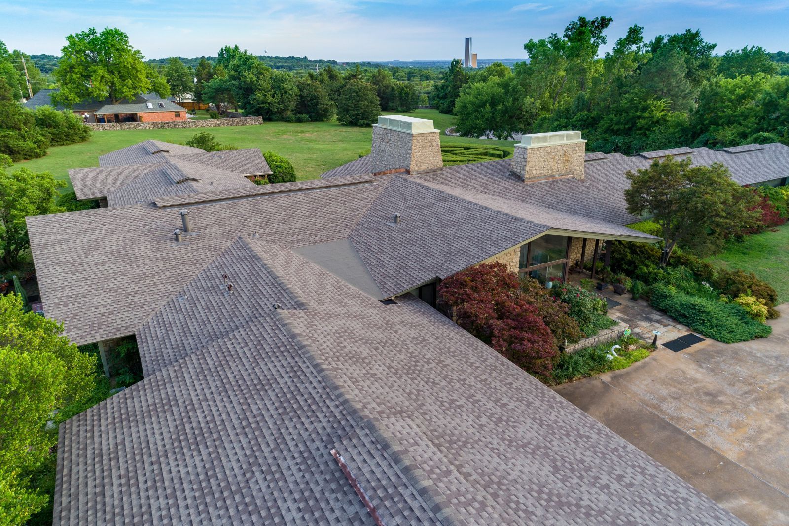An aerial view of a large house with a large roof surrounded by trees.