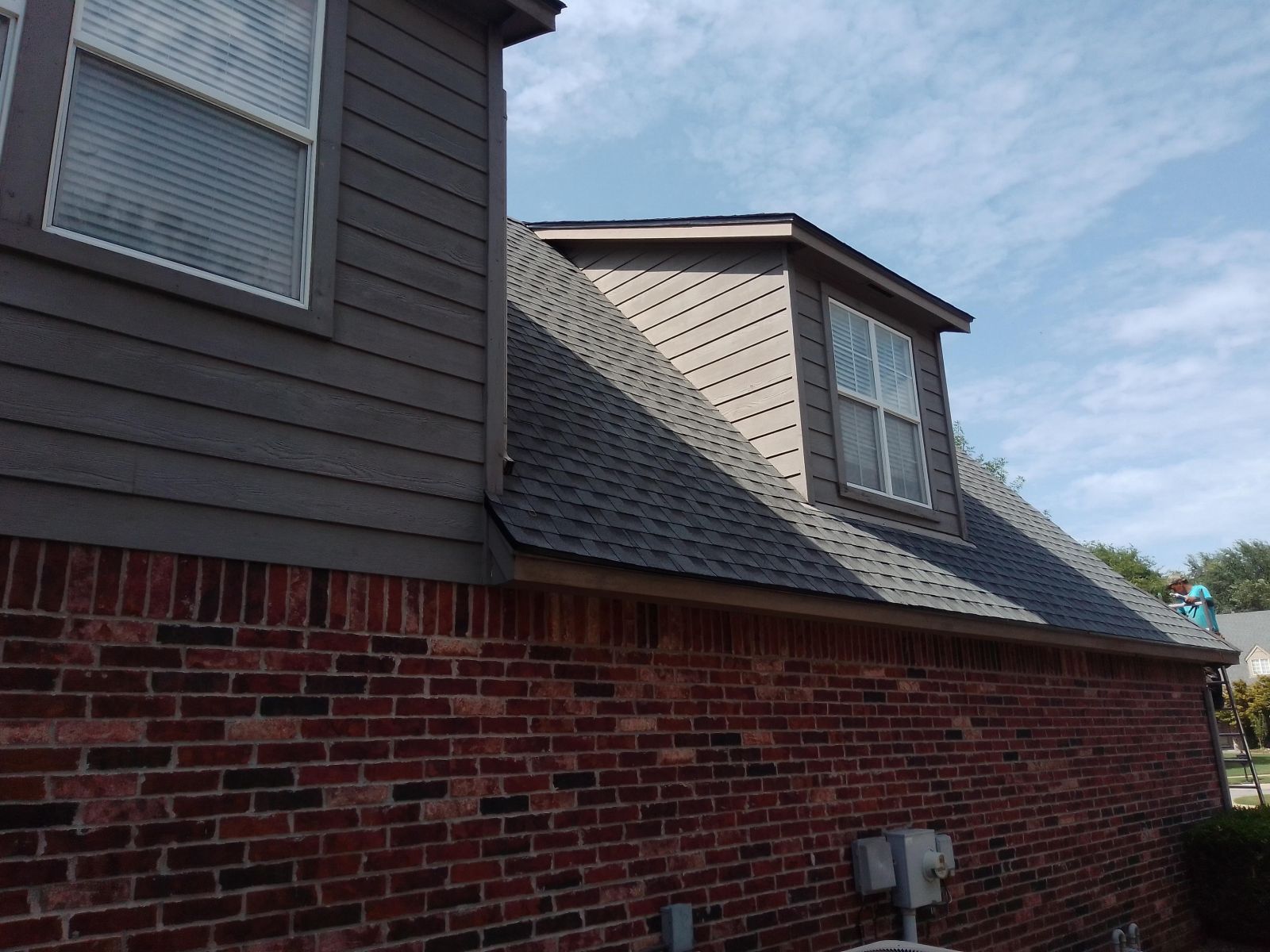 A brick house with a roof that has a window on it