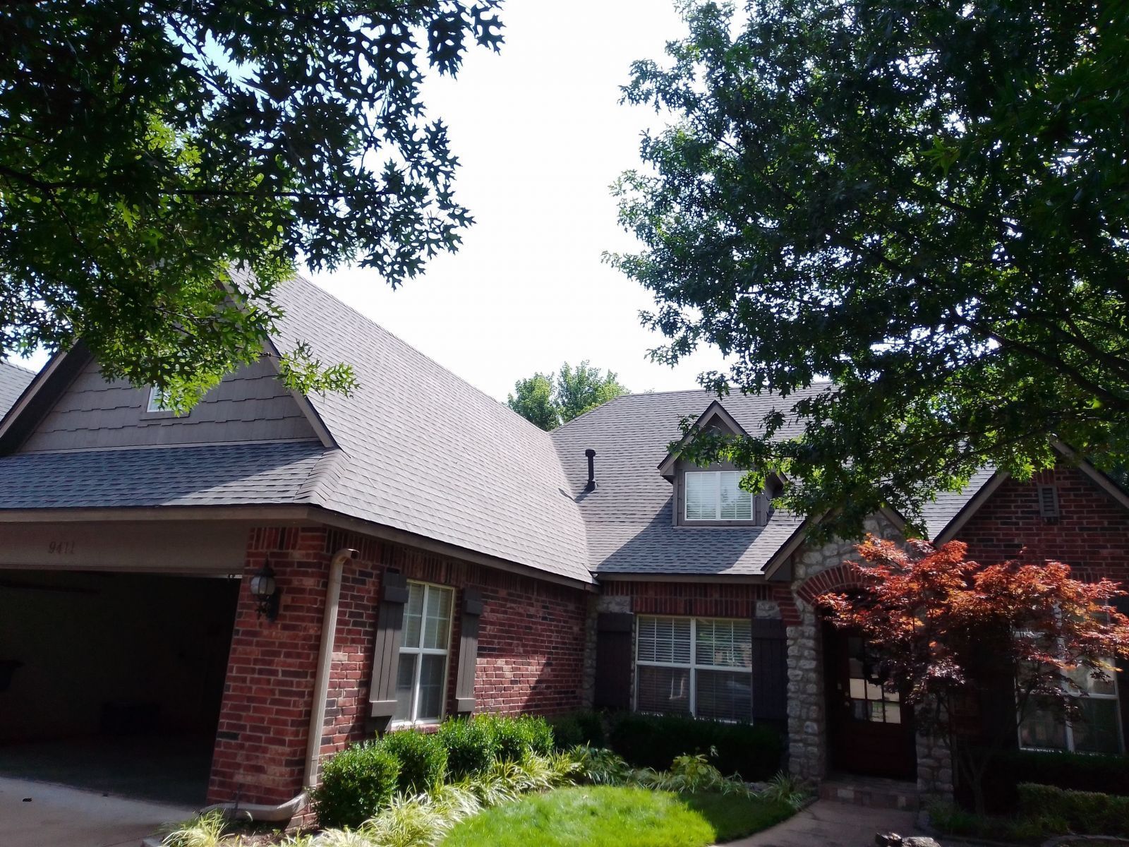 A brick house with a garage and a tree in front of it