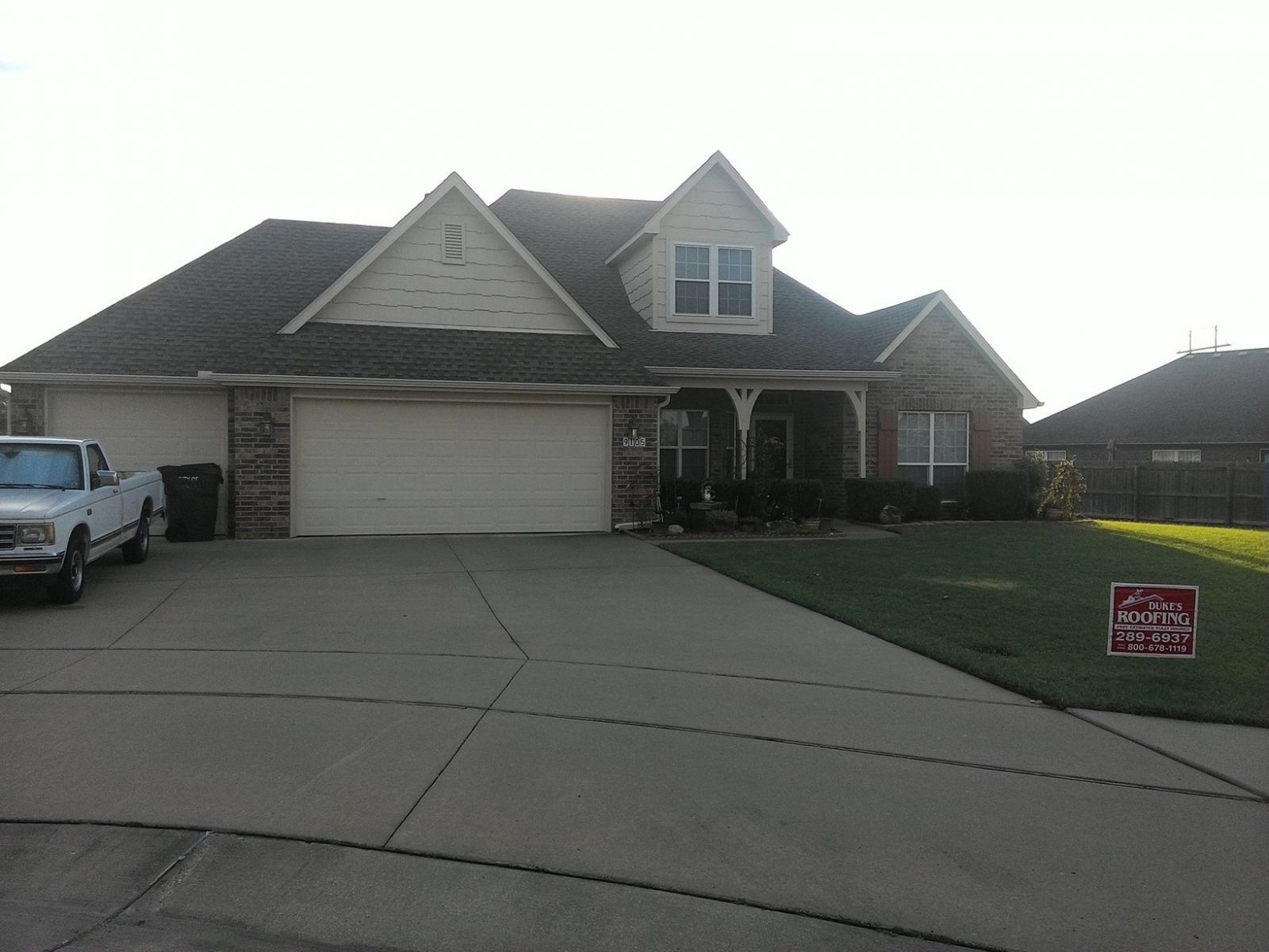 A white truck is parked in front of a large house