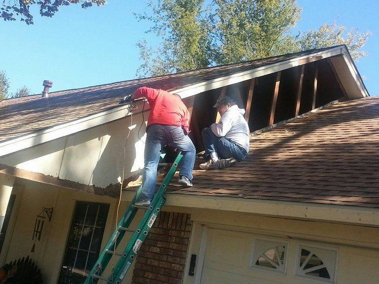 Two men are working on the roof of a house