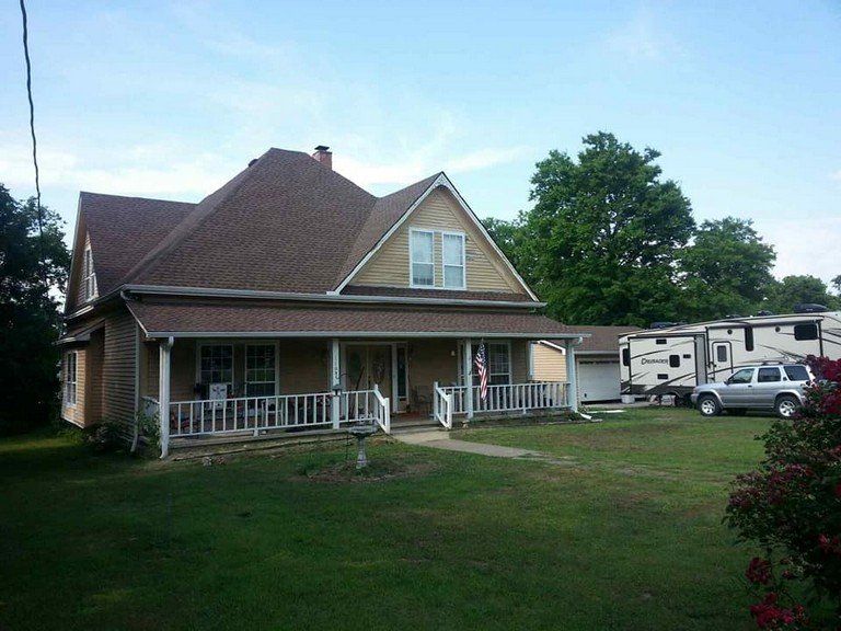 A house with a porch and a trailer parked in front of it