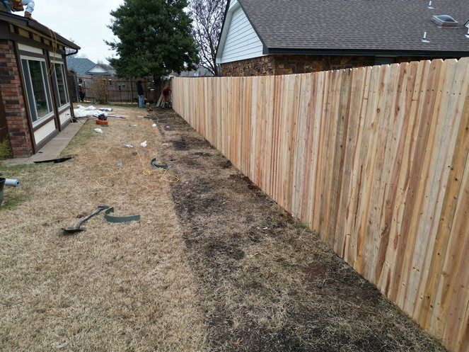 A wooden fence is being built in the backyard of a house.