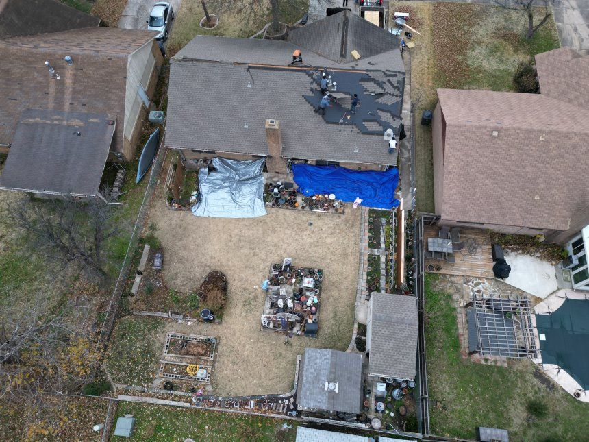 An aerial view of a house with a blue tarp on the roof