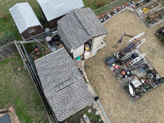 An aerial view of a backyard with a lot of sheds and a fence.