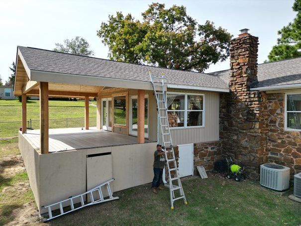 A man is standing on a ladder in front of a house.