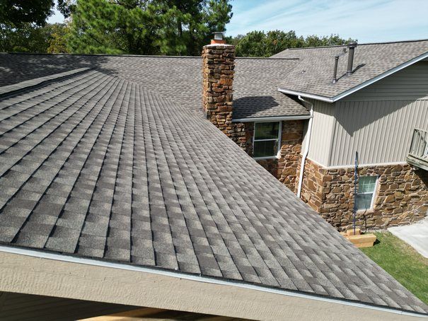 A house with a gray roof and a chimney on the side.