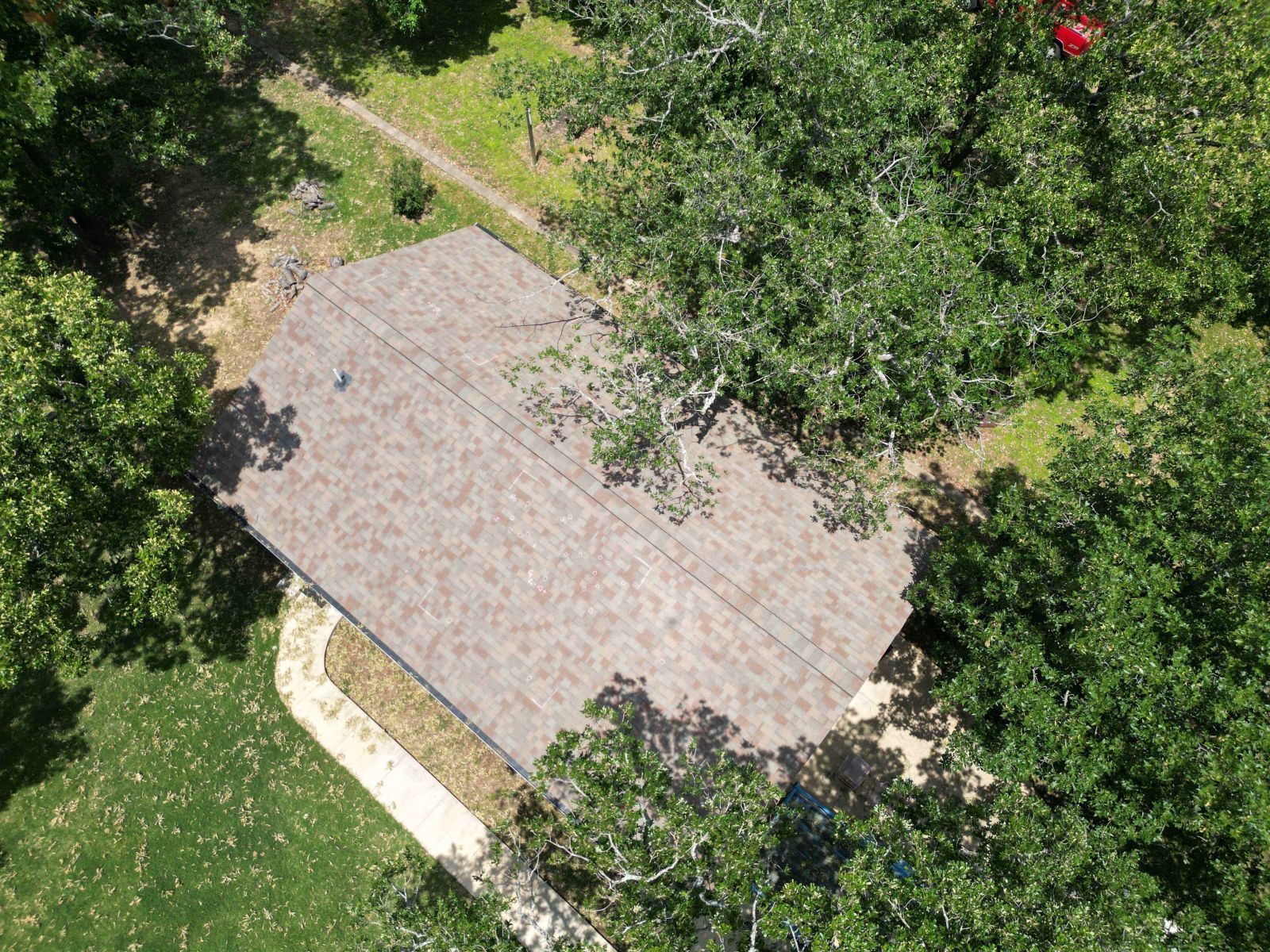 An aerial view of a house surrounded by trees and grass.