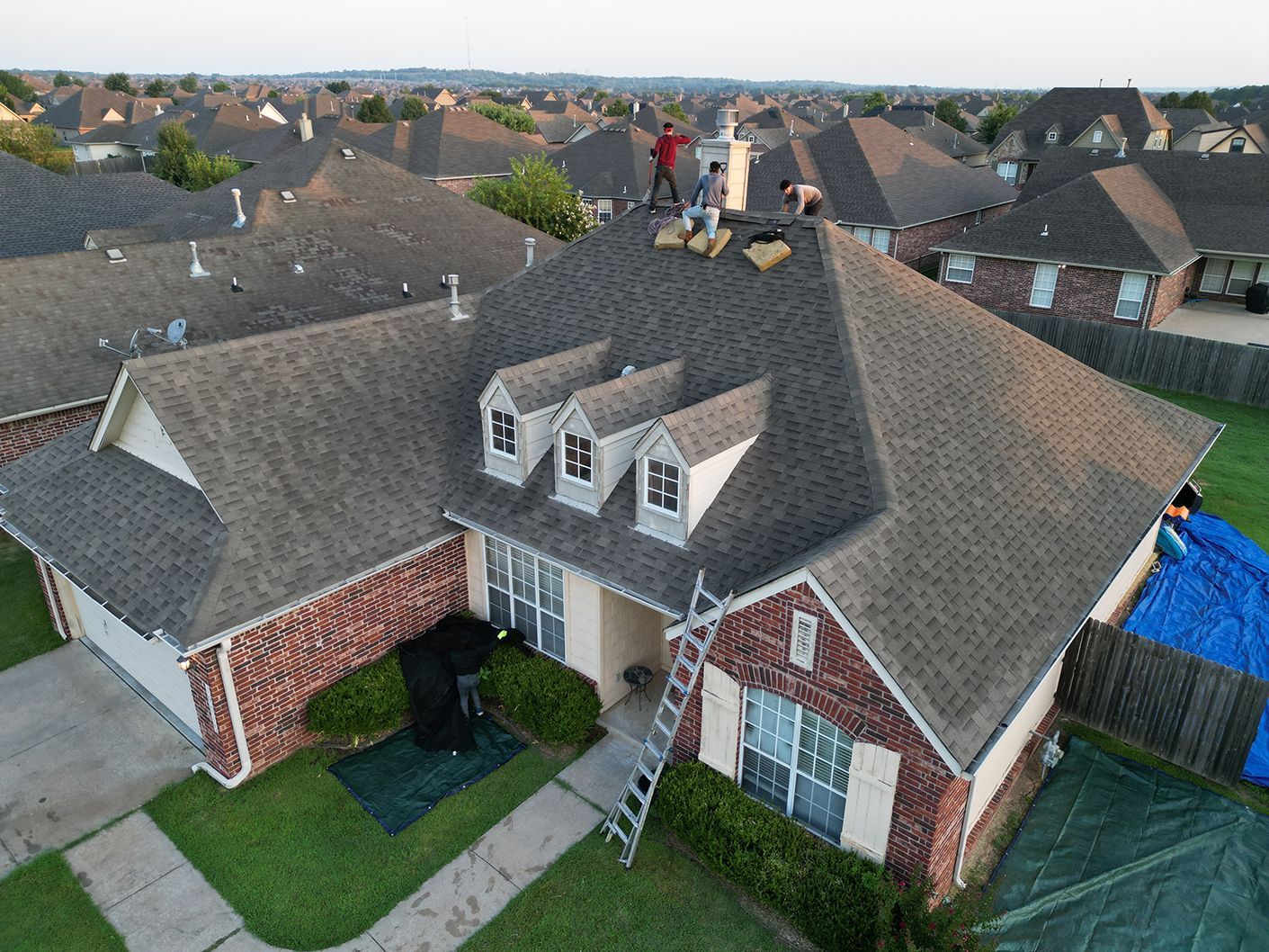 An aerial view of a house with a man standing on the roof.