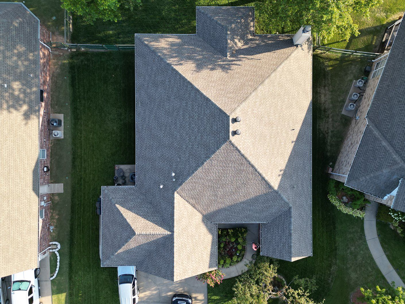 An aerial view of a house with a roof and a car parked in front of it.