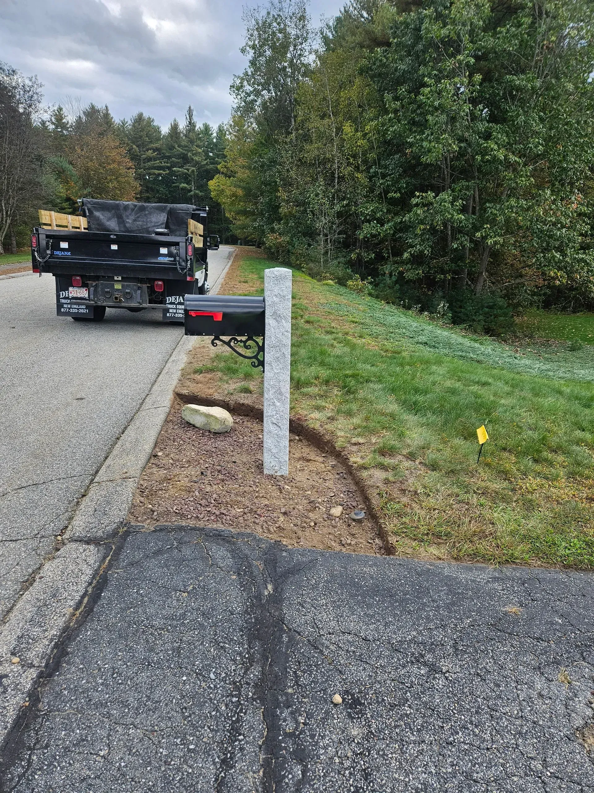 Truck parked on gravel road beside a white post and grassy verge under cloudy skies