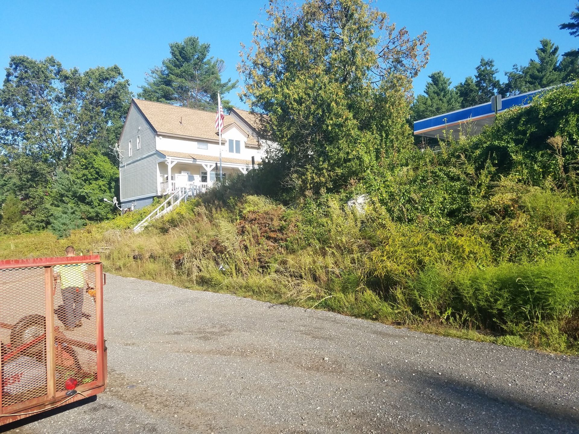 House on a hillside beside a gravel road under a clear blue sky
