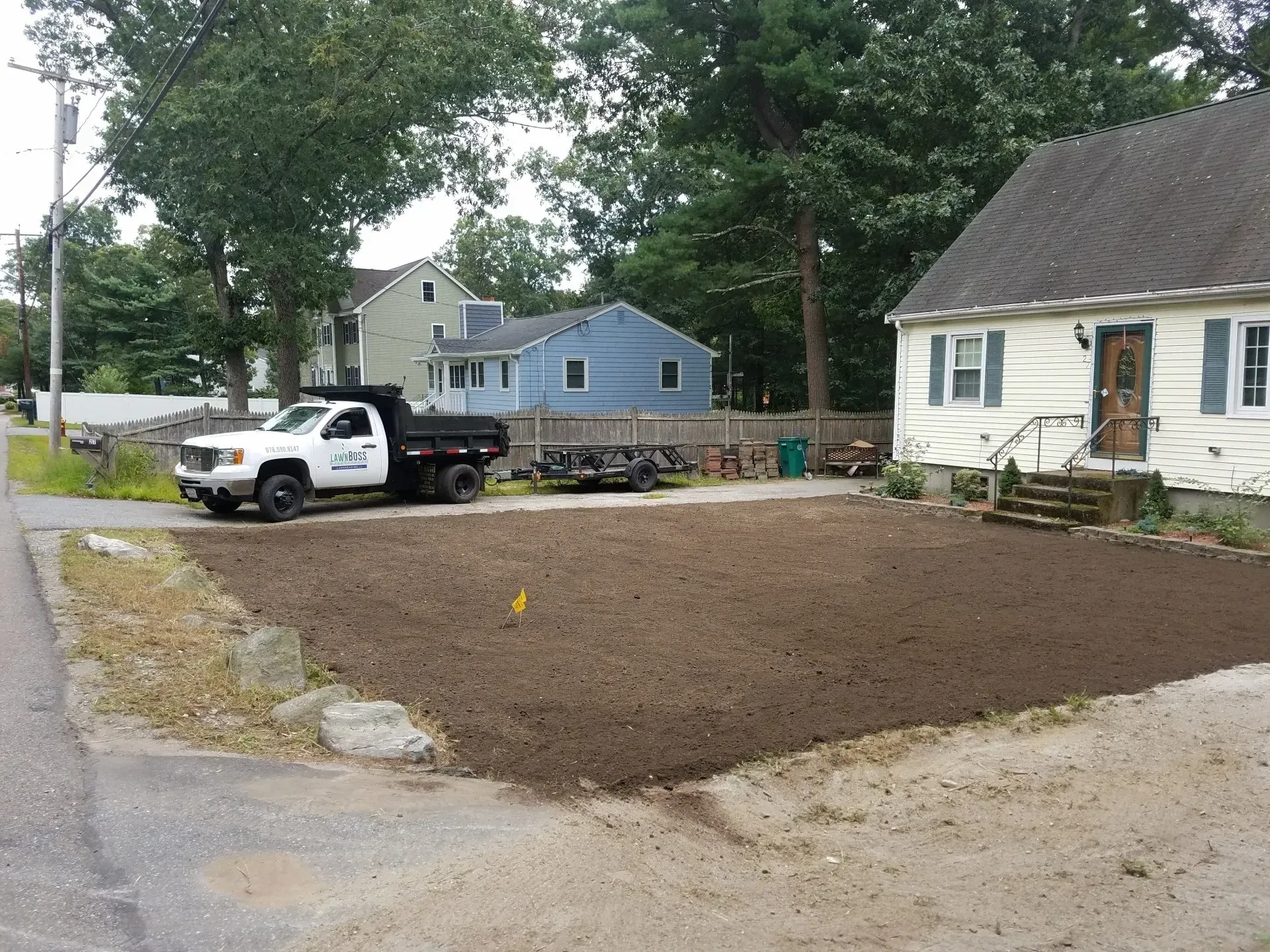 Driveway and yard with a white pickup truck beside a house on a quiet residential street.
