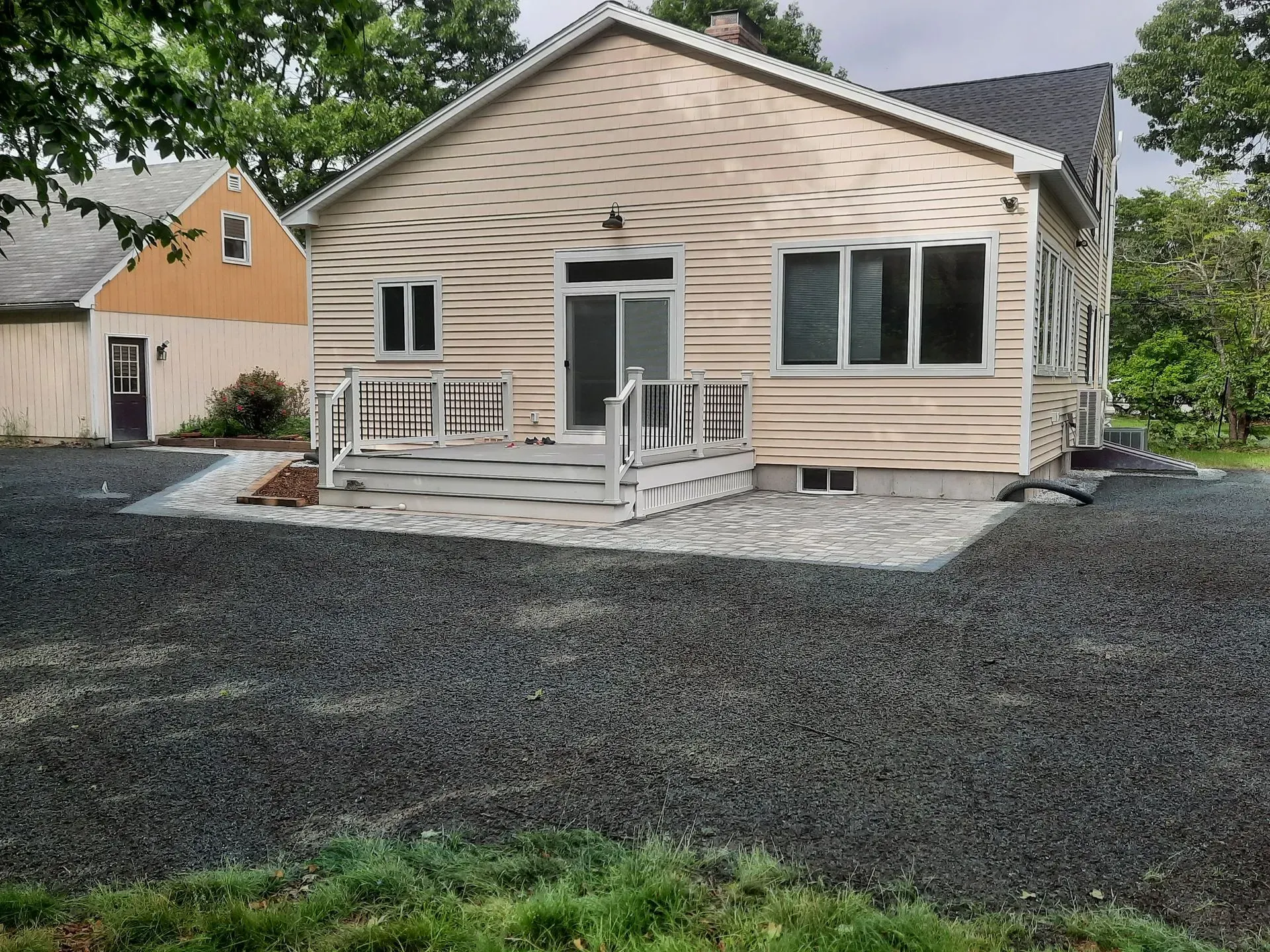 Beige house with white trim, small front porch, and newly landscaped dark gravel yard.