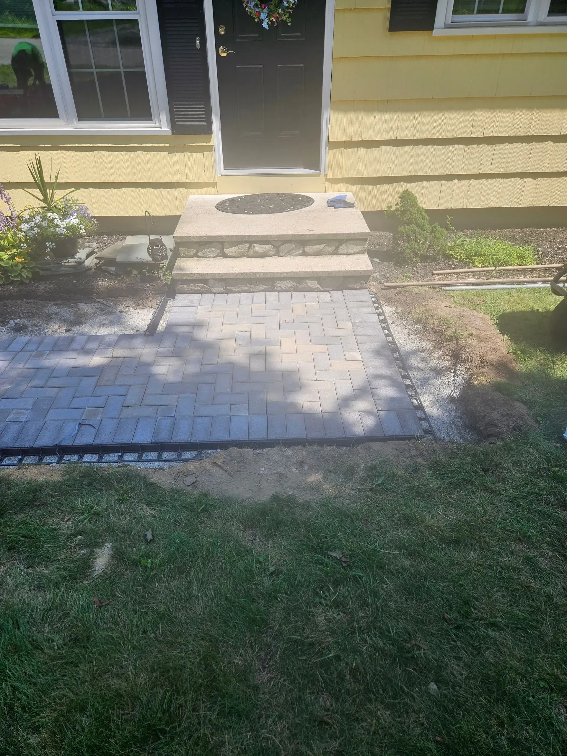 Front steps and walkway leading to a house door, with grass and shrubs on either side.