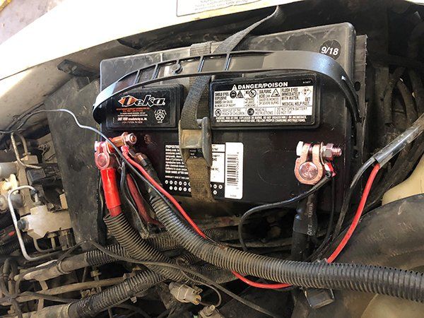 A car battery is sitting under the hood of a car.