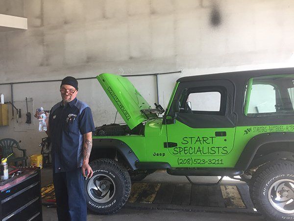 A man is standing next to a green jeep that says start specialists