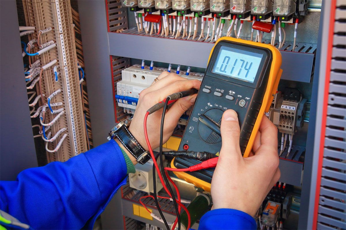 Technician testing electrical control panel with a digital multimeter