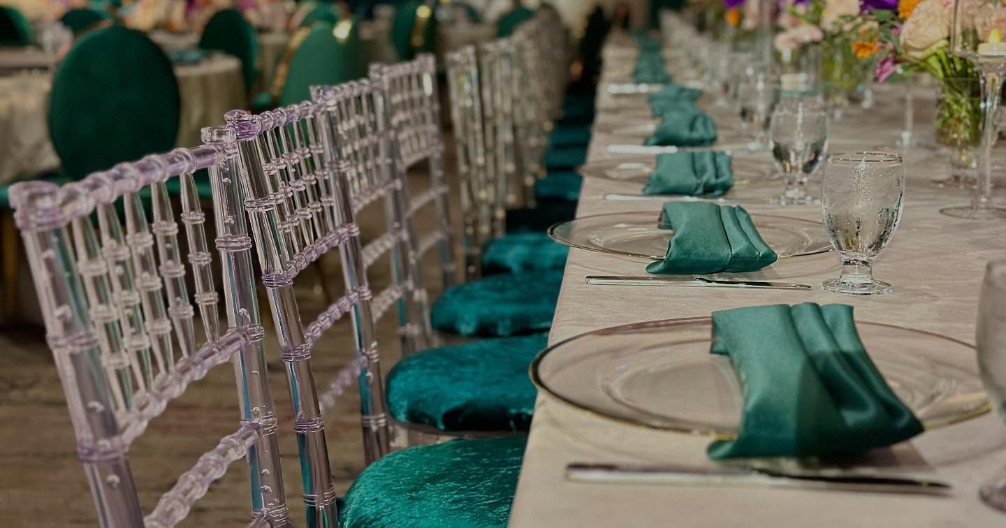 Long table set for a formal event, turquoise accents, clear chairs.
