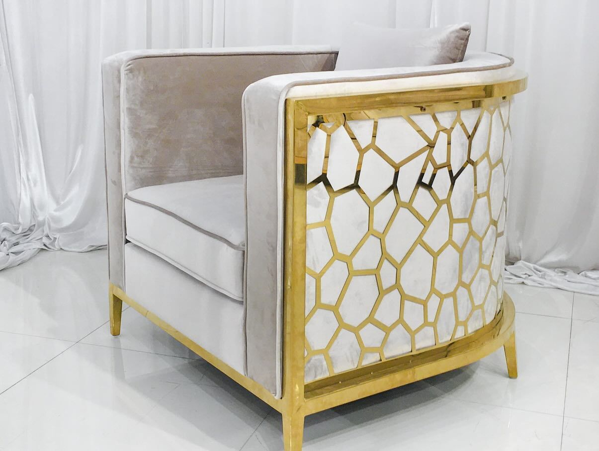 Beige velvet armchair with gold accents and a decorative back panel.