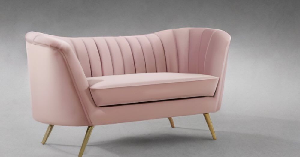 Pink velvet loveseat with gold legs, set against a gray backdrop.
