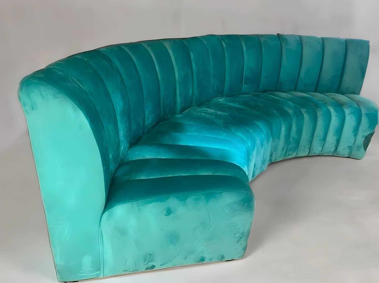 Turquoise curved velvet sofa with vertical ribbed back.