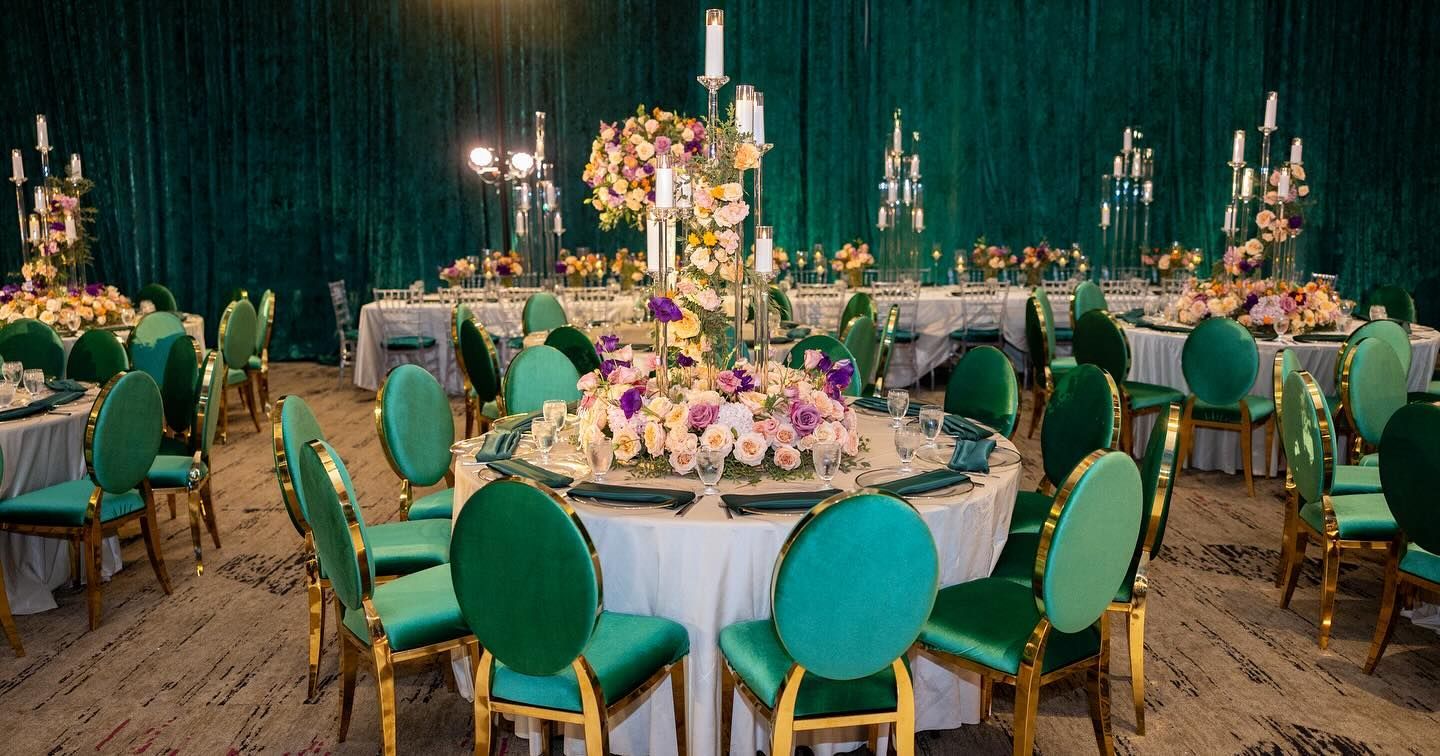 Banquet hall with emerald green chairs, tables, and decorations for a wedding.