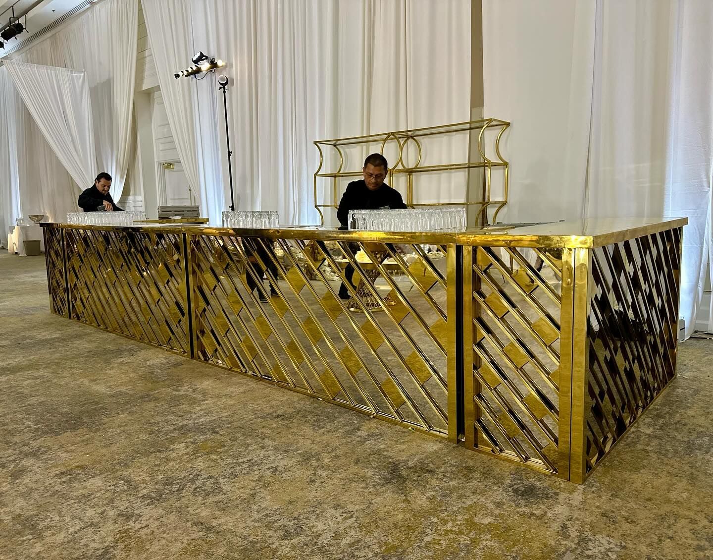Gold-colored bar with two bartenders in a decorated venue.