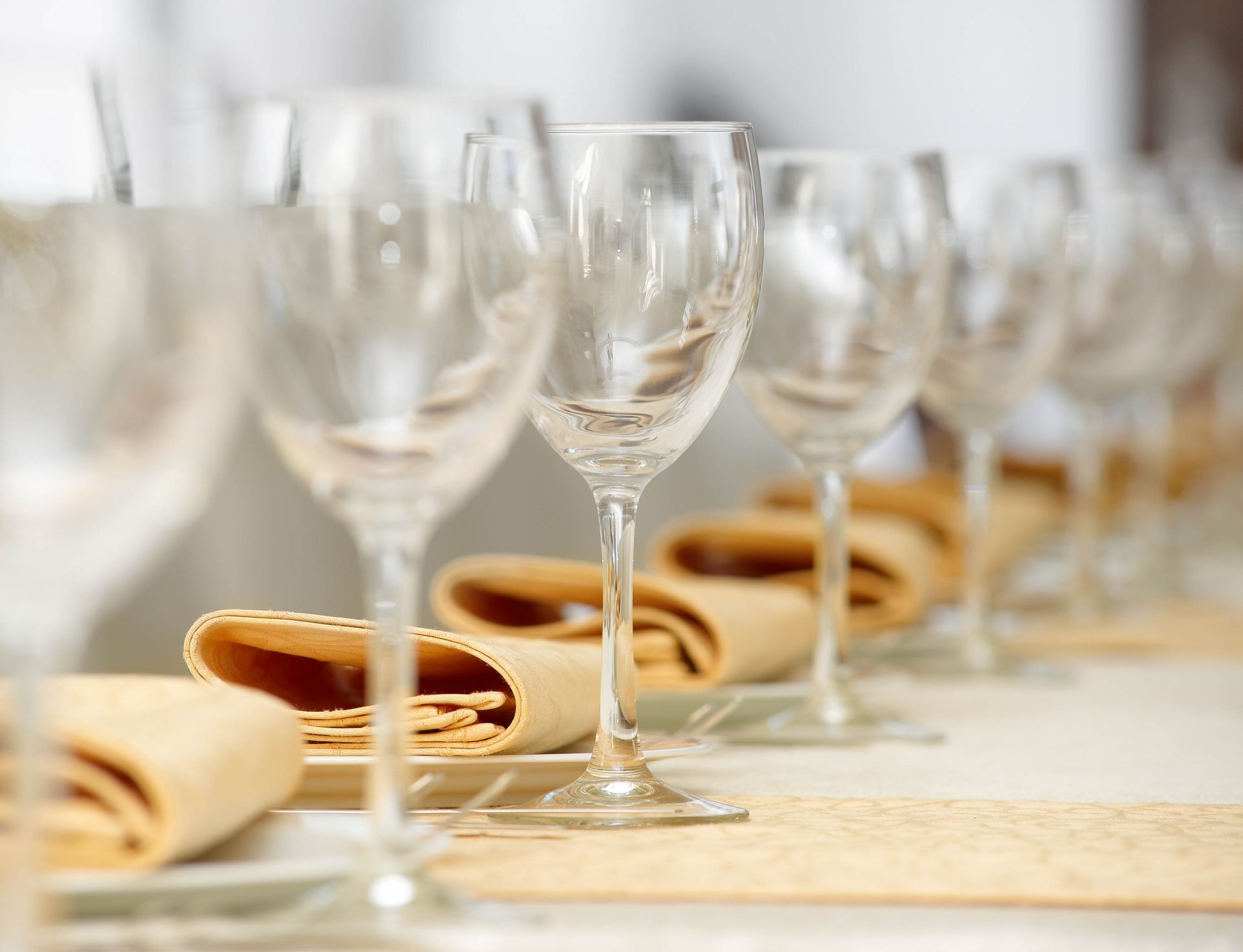 Wine glasses and folded napkins set on a table, ready for a meal.