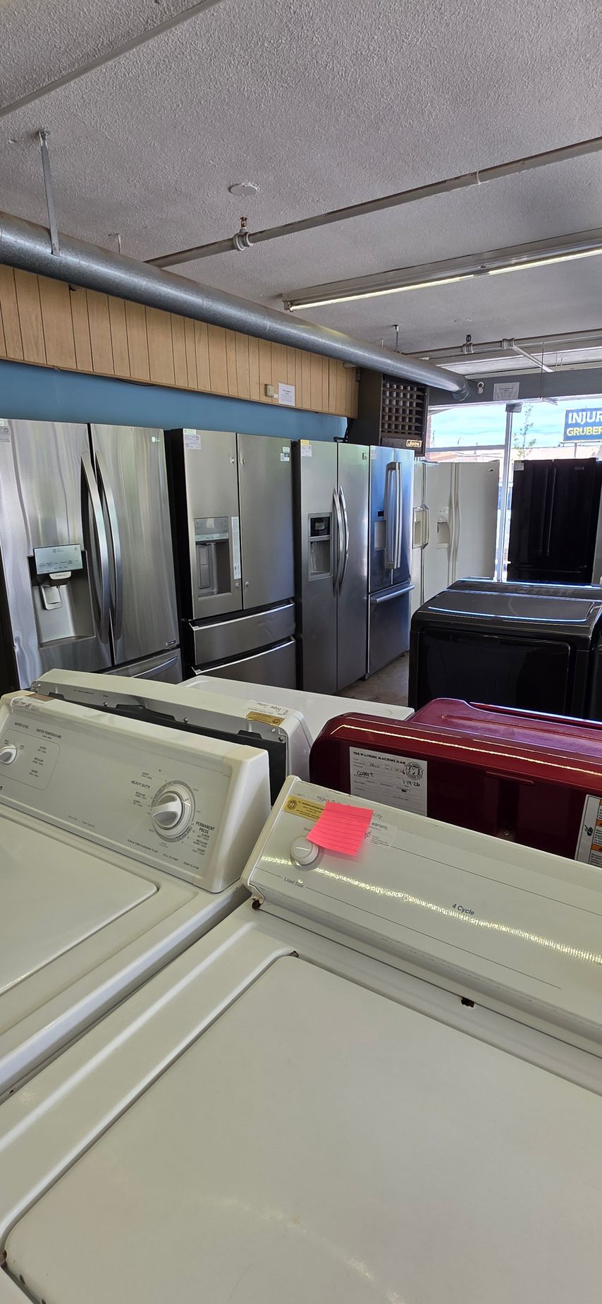 Laundry room with rows of white washers and dryers and a red cart in the foreground