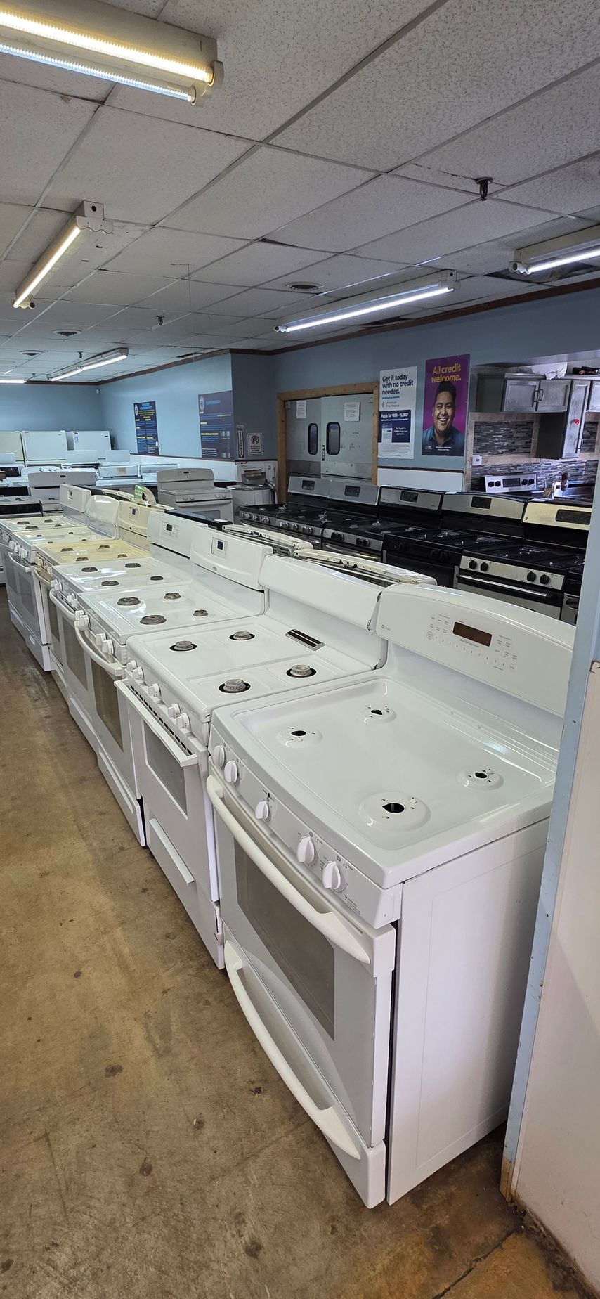 Empty laundromat with rows of white washing machines and fluorescent ceiling lights