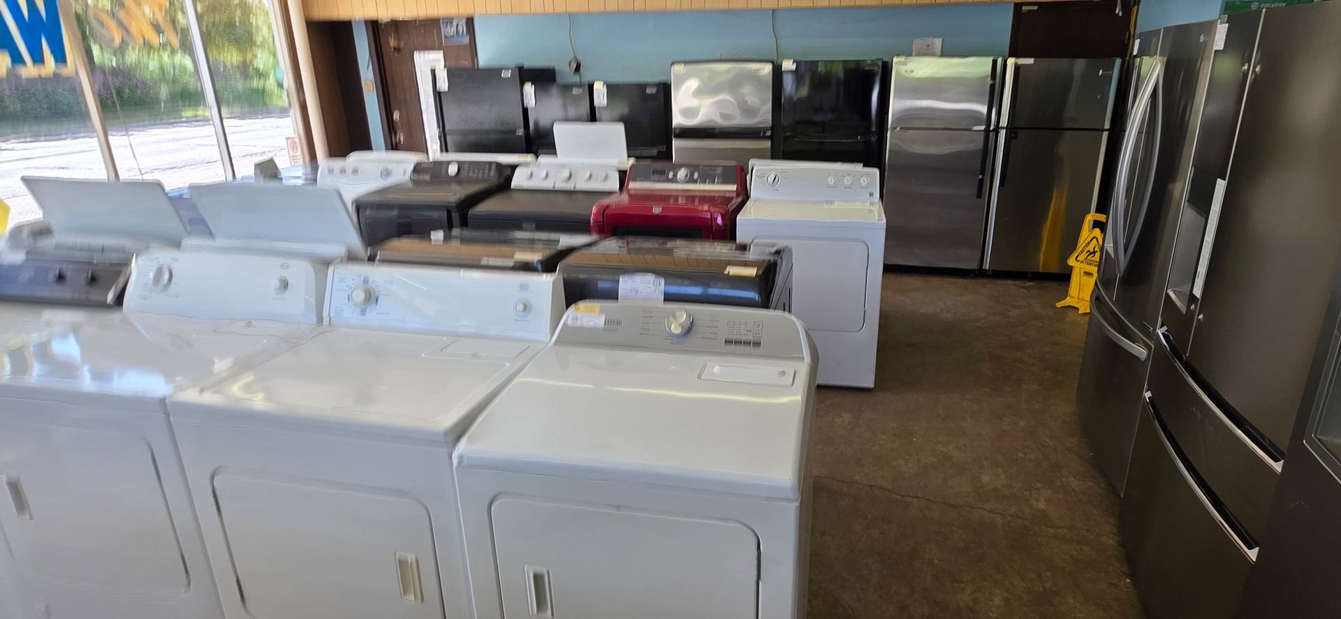 Laundry room with rows of white washing machines and dryers under fluorescent lights