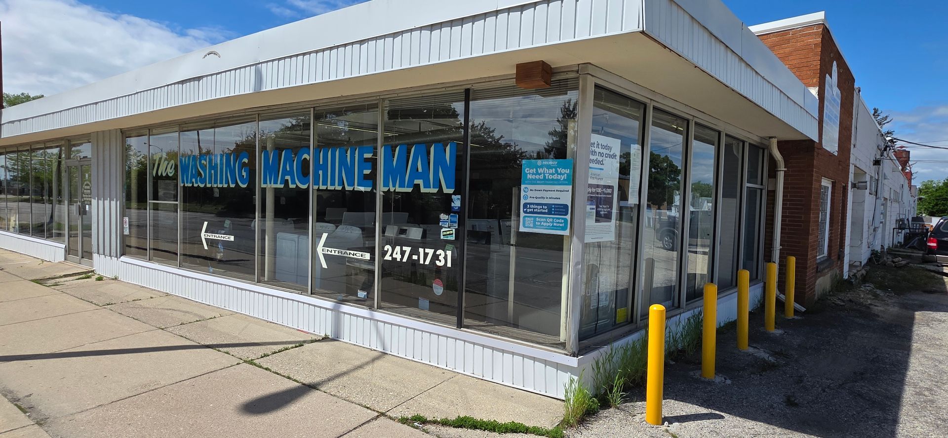 Storefront with large windows and blue signage on a sunny street corner