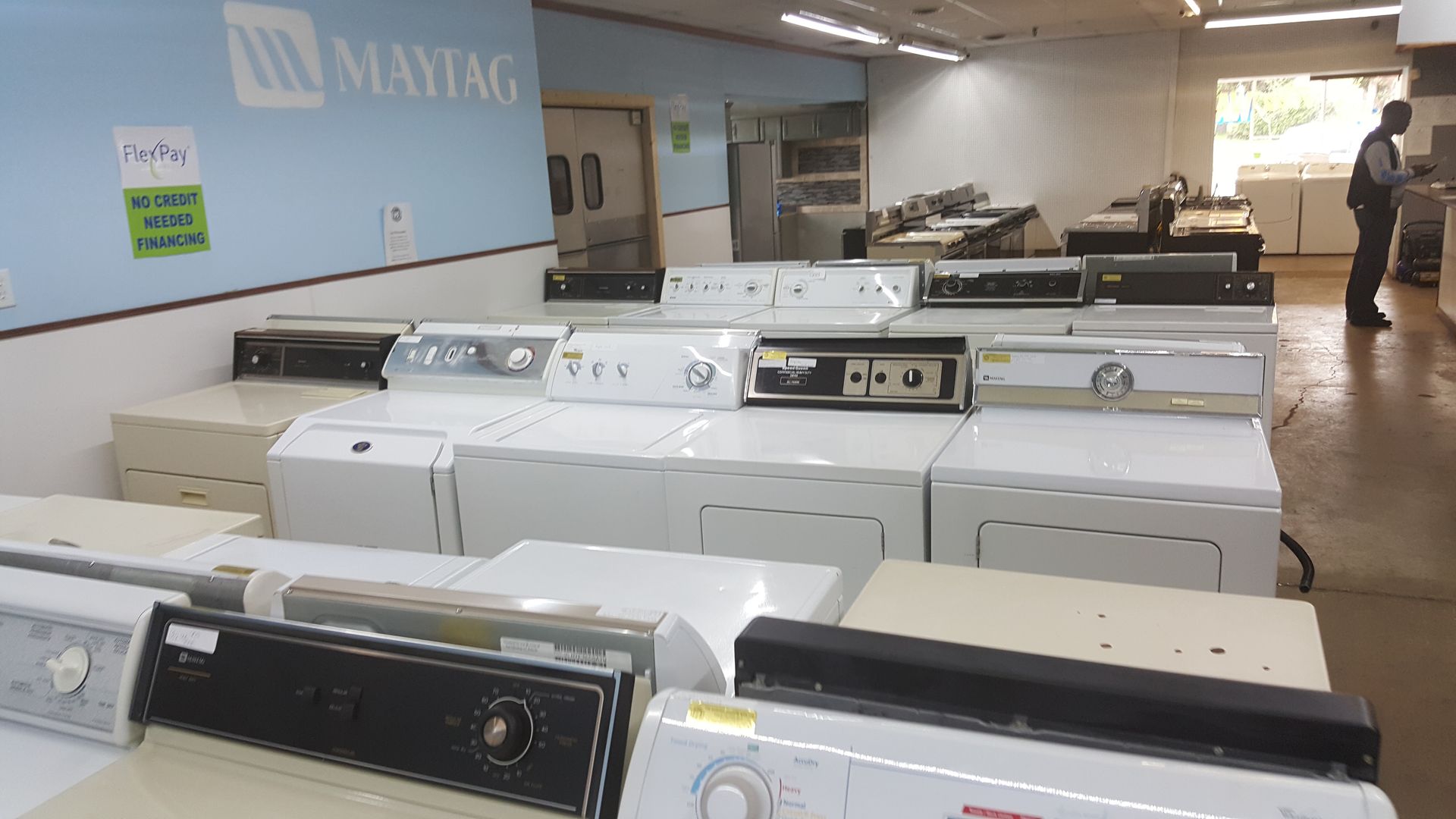 Rows of white Maytag appliances in a showroom, with washing machines and dryers displayed.