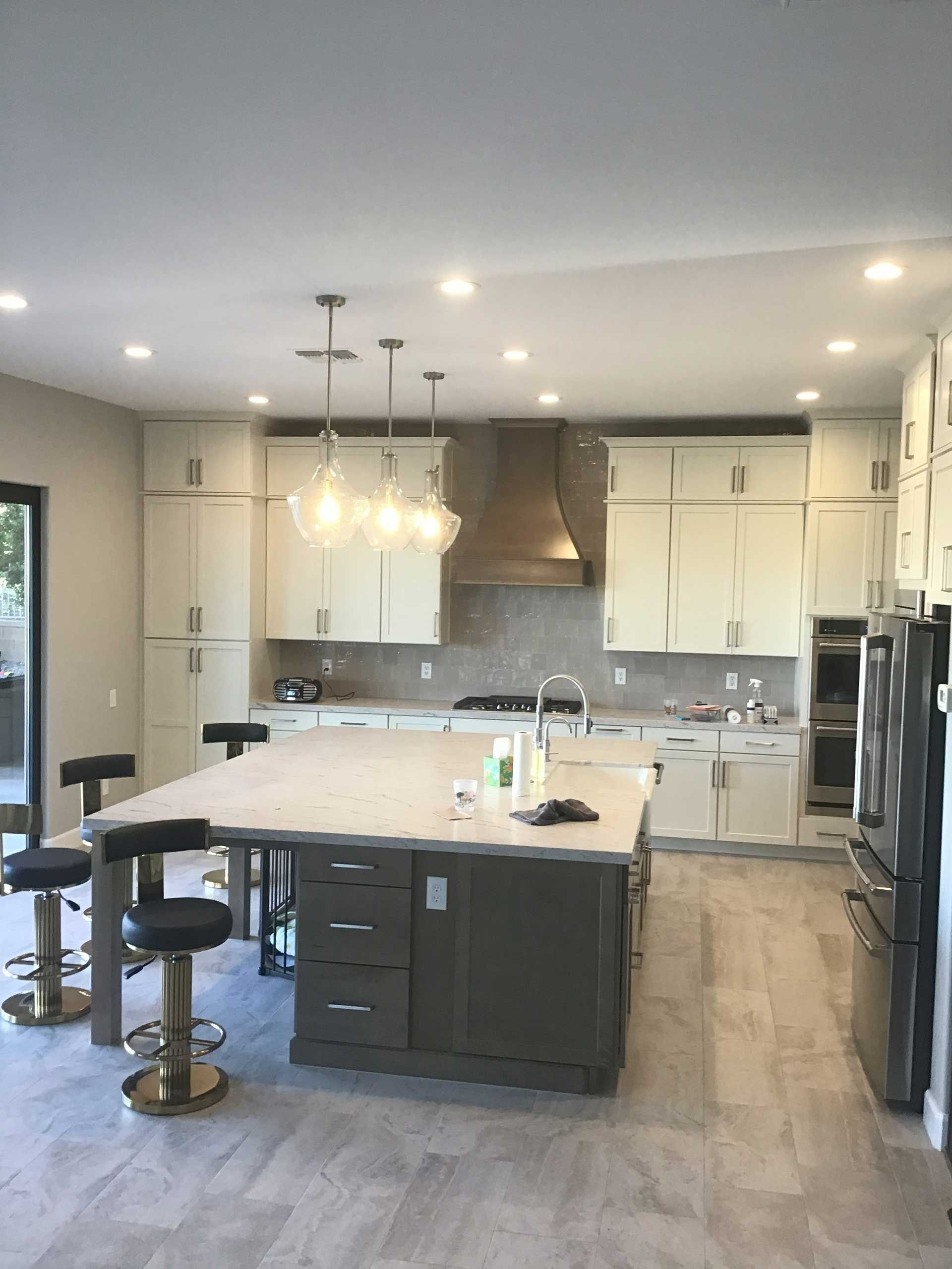 modern kitchen with large island, light cabinets, stainless steel appliances, and pendant lights over the island