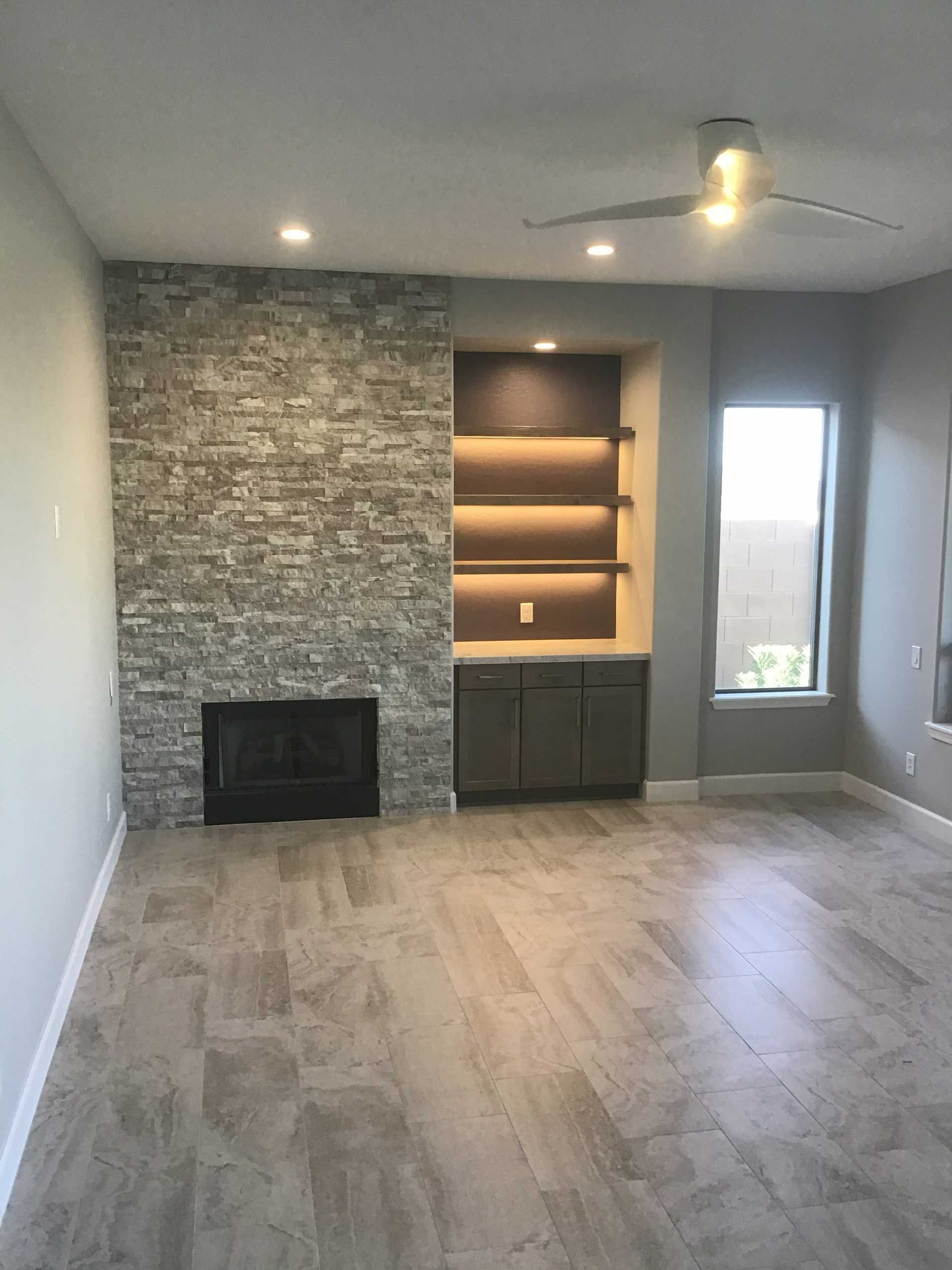 a modern living room featuring a stone fireplace and built-in shelves with cabinets