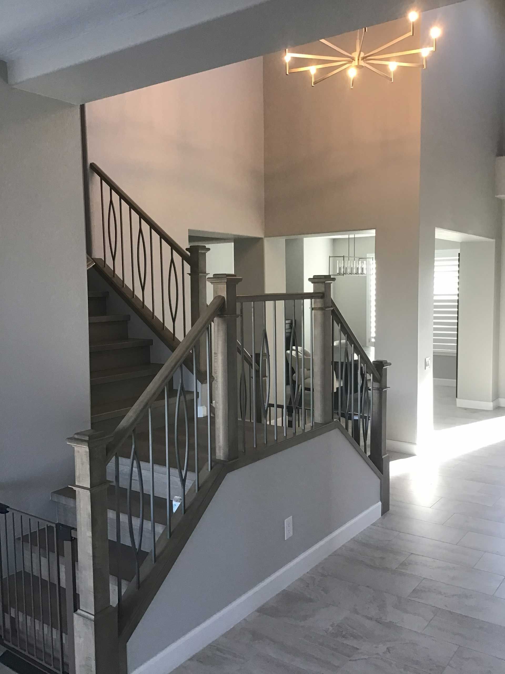 interior view of a staircase with gray and white details, lit by a modern chandelier