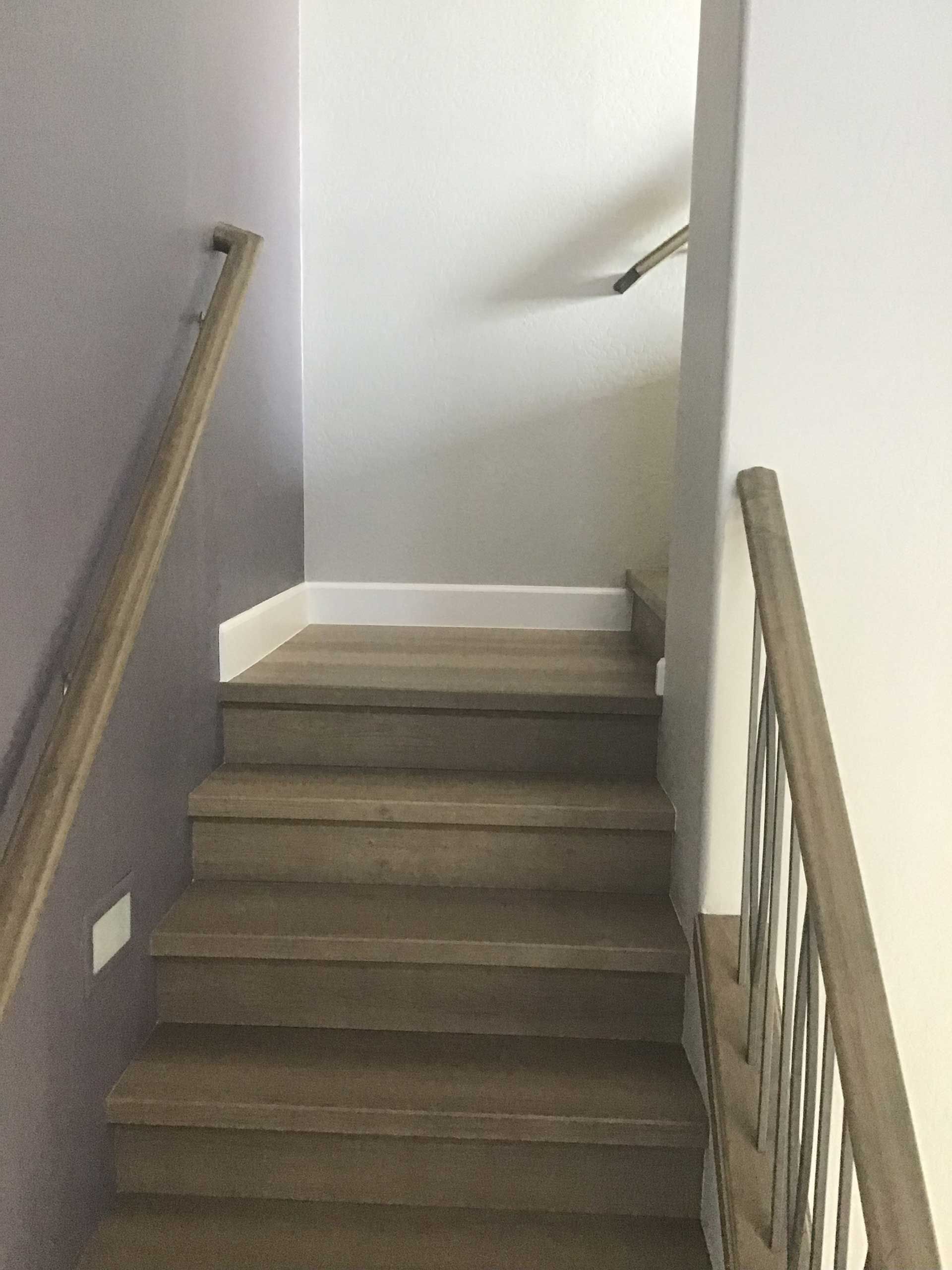 staircase with wooden steps and handrails, ascending toward a landing with white trim, walls are purple and white
