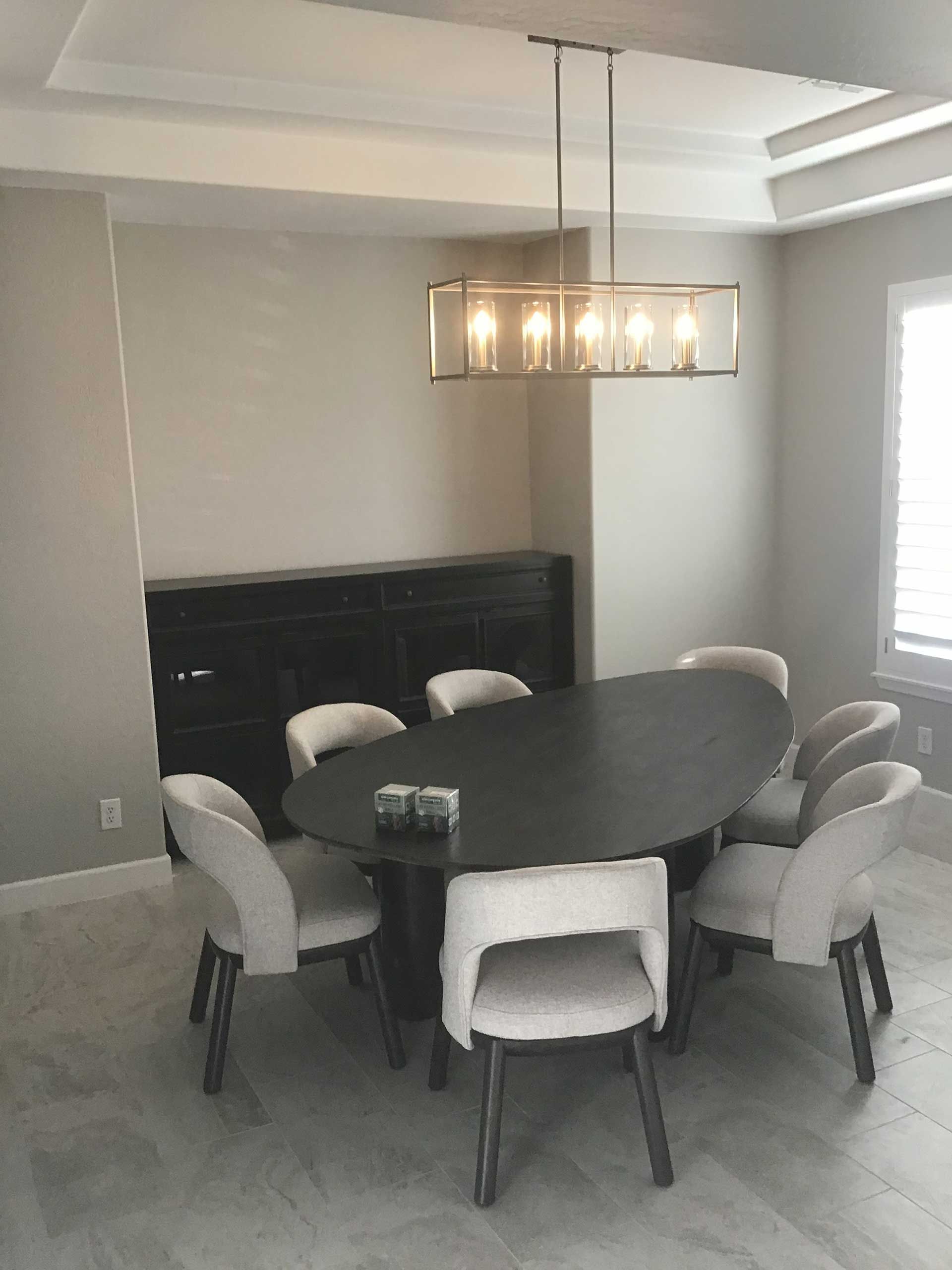 a dining room with a dark oval table, cream chairs, and a rectangular chandelier
