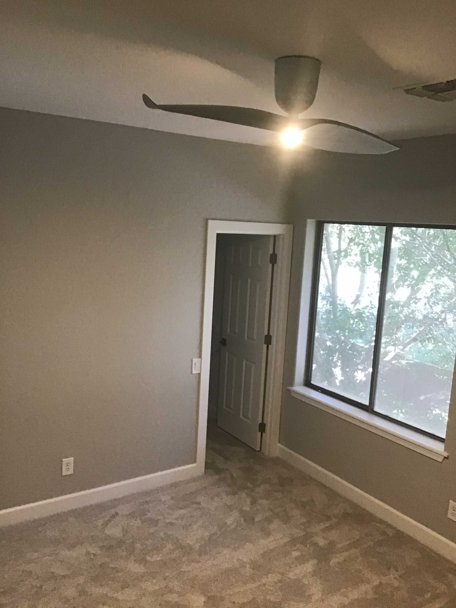 a bedroom with gray walls, carpet, and a ceiling fan
