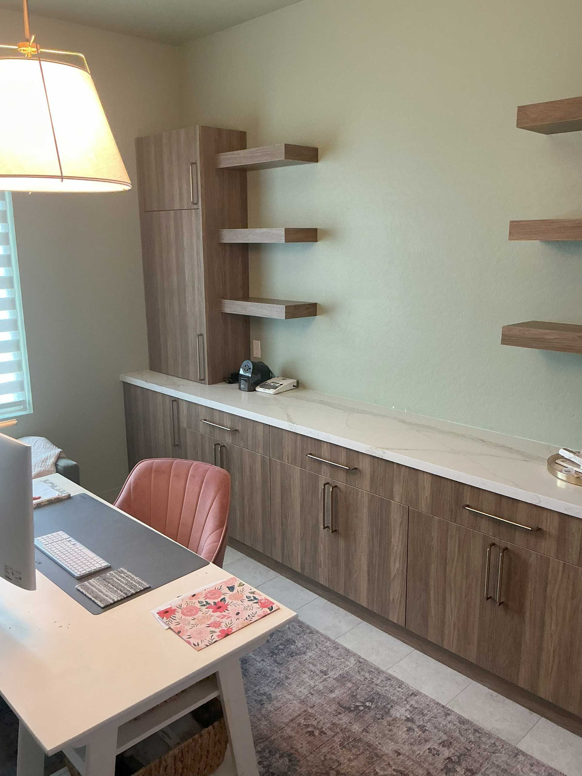 home office with built-in wood cabinets and shelves against a light green wall
