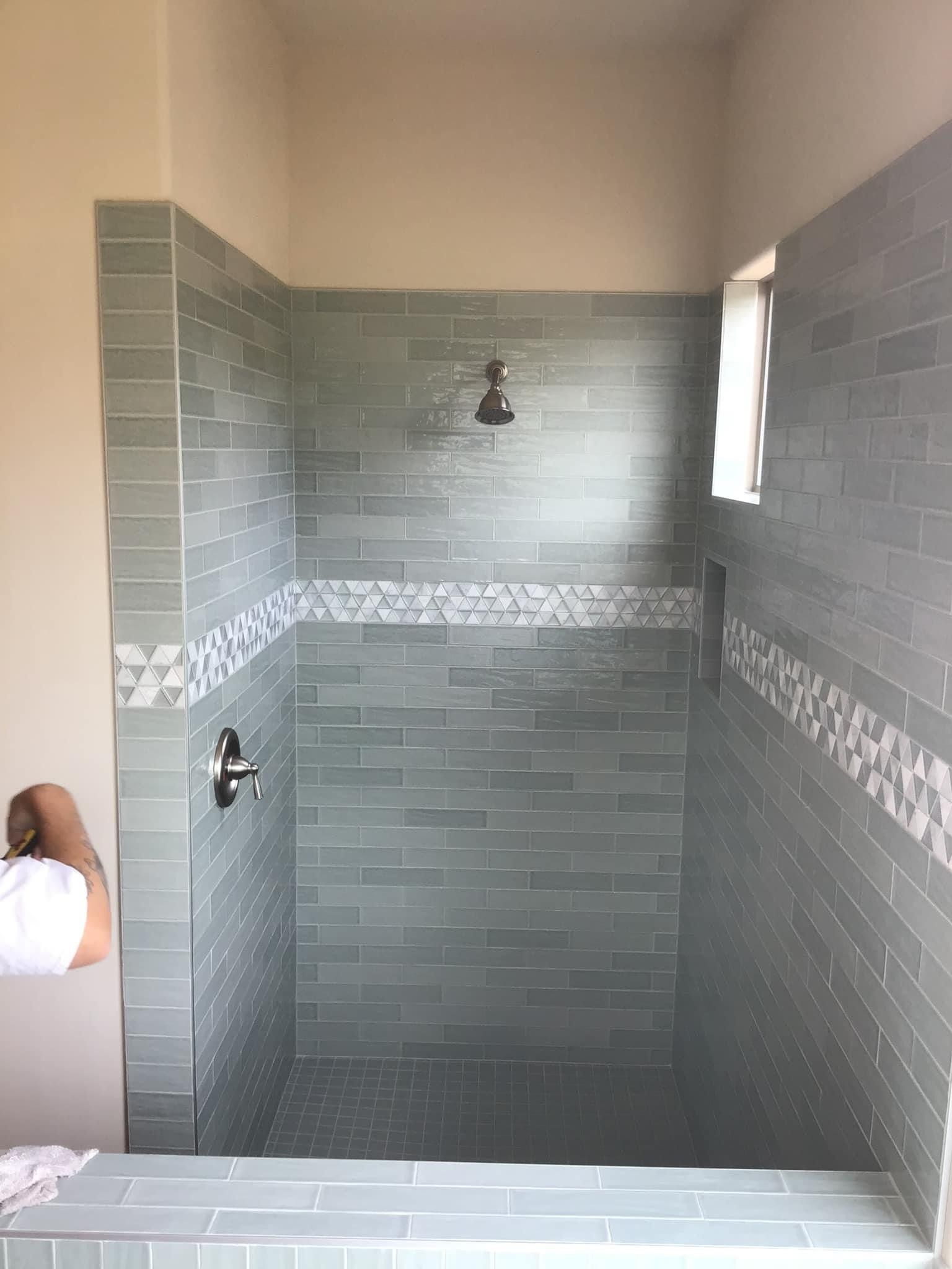 a tiled shower with a decorative mosaic tile band