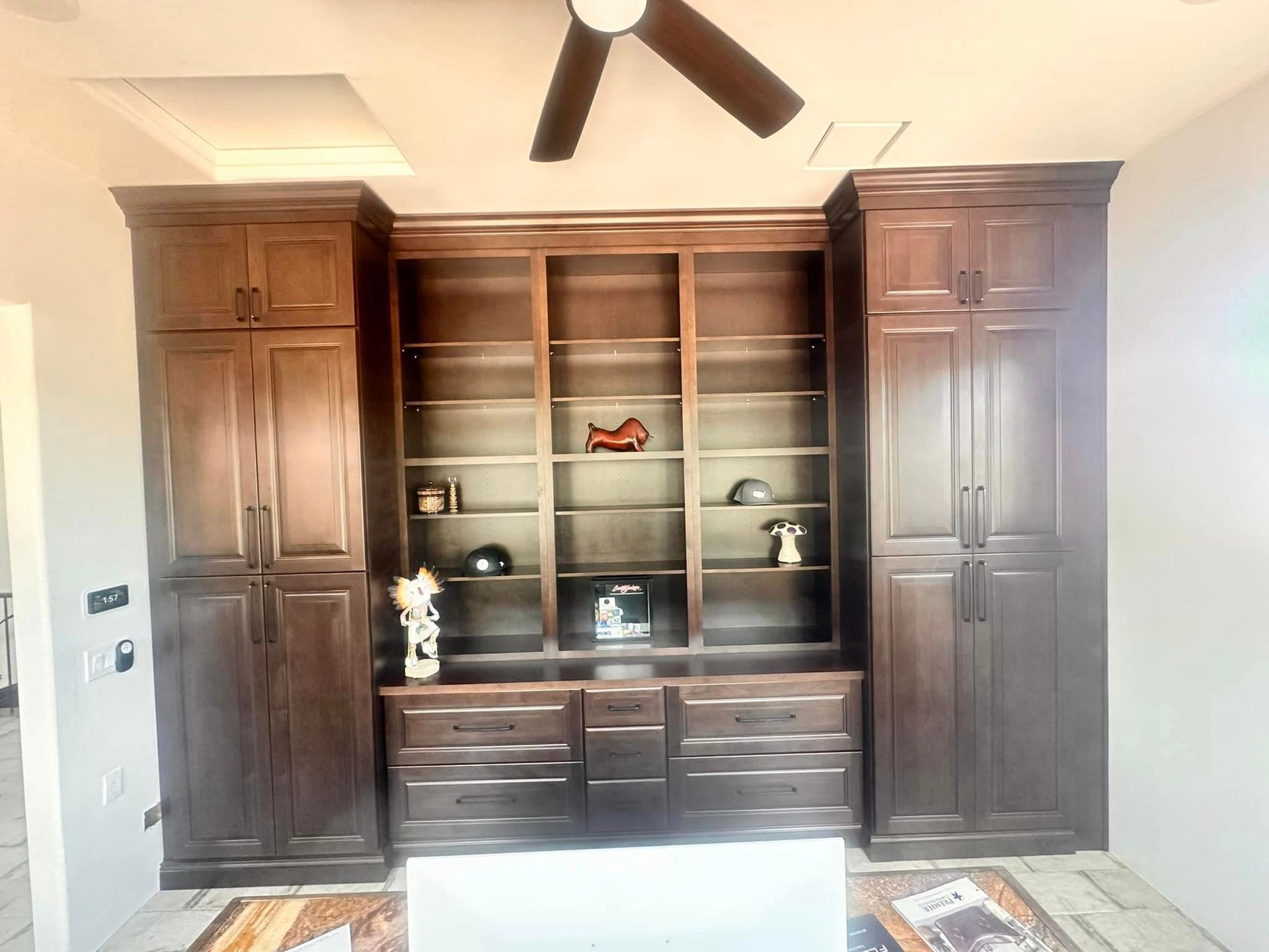 A room with a lot of cabinets and shelves and a ceiling fan.